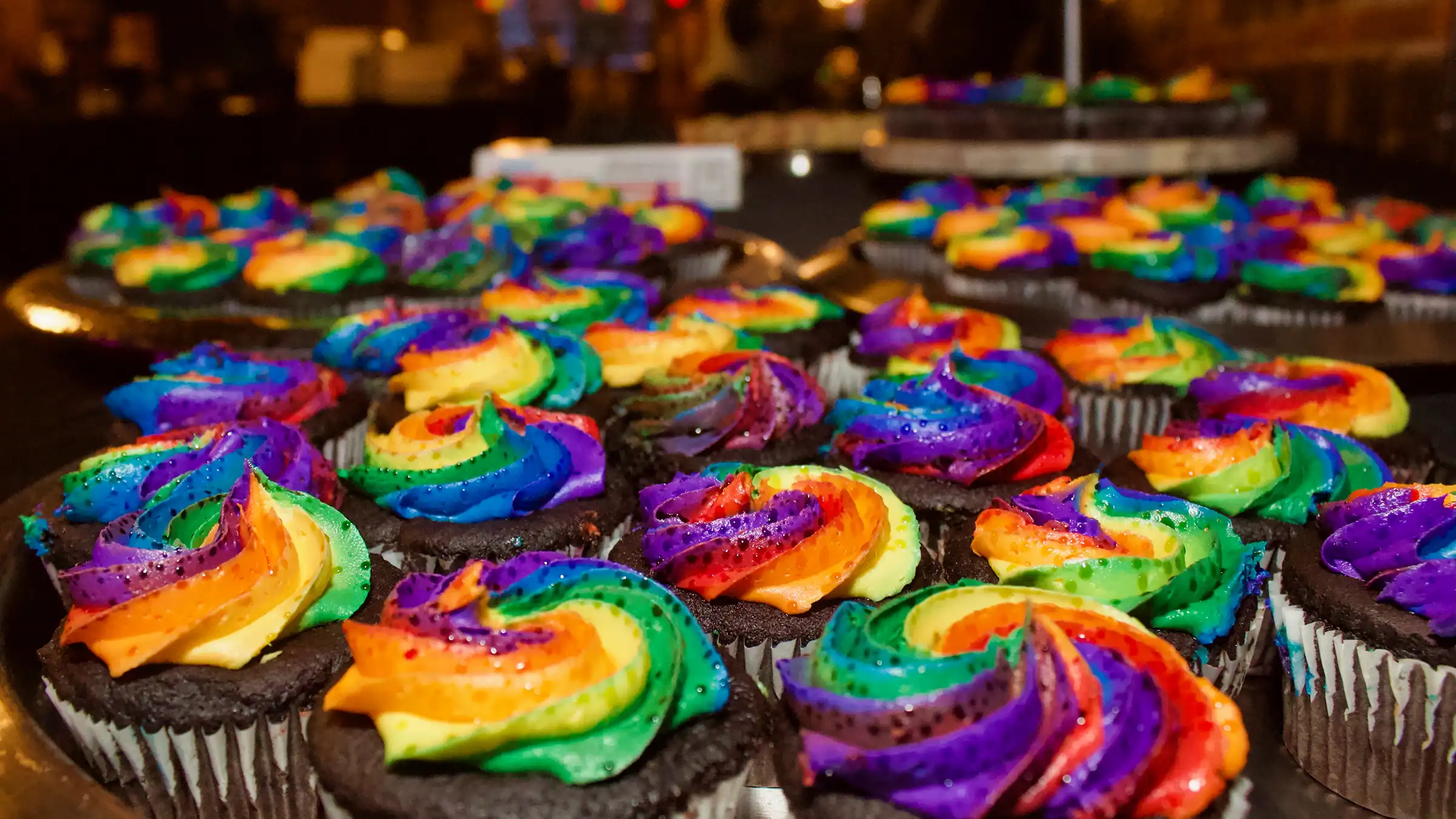 Taste of Pride Banner Dozens of rainbow frosted chocolate cupcakes.